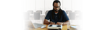 Adult African American male using a teletyprwriter to make a telephone call.